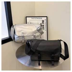 Two messenger bags in black and light gray on a metal stand with utility buckles