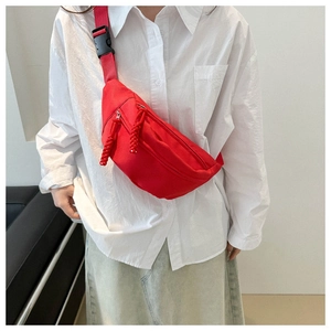 Detail of red canvas crossbody bag with braided zipper pull and adjustable strap