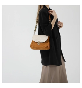 Detail view of contrast patchwork shoulder bag featuring chain strap and metal lock closure