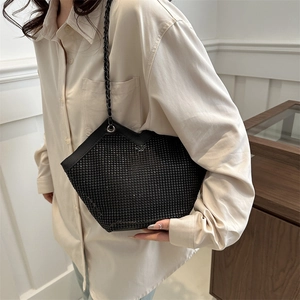 Sac fourre-tout tendance noir avec strass porté par un mannequin dans un cadre minimaliste