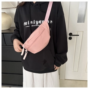 Detail view of pink nylon crossbody chest bag showing water-resistant material and woven strap