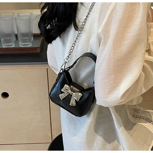 Detail of a mini black PU bag featuring a silver bow buckle and elegant metal chain strap