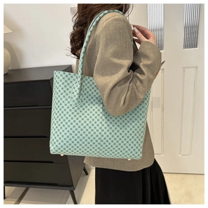 Detalle de bolso tote verde menta con motivos geométricos y tacos de protección dorados abajo
