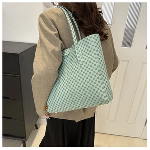 Detalle de un bolso tote verde menta con patrón circular llevado por una modelo real