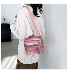 Borsa a tracolla rosa metallizzata con tasca a zip e ampia tracolla indossata da un modello