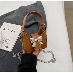 Detail of a brown PU mini bag featuring a silver metal bow buckle and chain strap