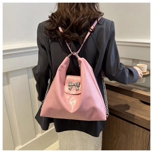Détail du sac à dos en cuir rose avec nœud métallique argenté et bandoulière chaîne