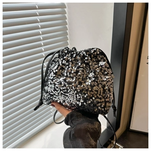Détail d'un sac seau à paillettes argentées avec fermeture à cordon et bandoulière noire
