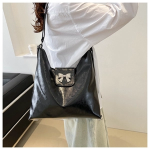 Détail d'un grand sac fourre-tout noir brillant avec un ornement de nœud en métal argenté