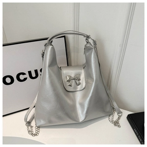 Détail du sac hobo argenté avec un nœud décoratif et une bandoulière en chaîne