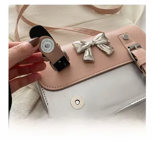 Close-up of the silver magnetic buckle closure and bow detail on the pink shoulder bag