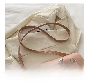 Detail of adjustable strap and silver bow on pink shoulder bag with office attire background