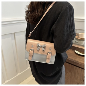 Detail view of contrast color crossbody bag with silver bow accent and metallic texture