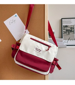 Detail view of canvas messenger bag with burgundy contrast and front zipper pocket