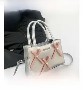 Détail du mini sac argenté avec des nœuds roses, des perles et le logo de la marque