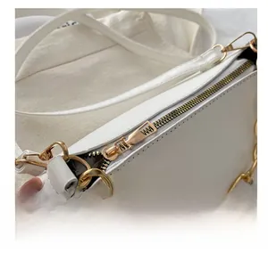 Close-up detail of smooth gold-tone metal zipper and high-quality PU leather strap on white bag