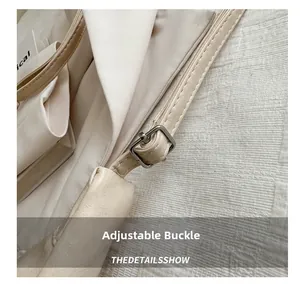 Detail shot of the adjustable shoulder strap with a square silver metal buckle on the tote bag