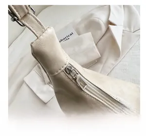 Detailed macro view of the smooth silver zipper and stitching on a beige leather tote bag