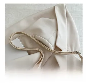 Detail of soft cream tote bag straps against an elegant blazer for a minimalist look