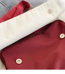 Detailed close-up of the red and white color-block canvas bag with magnetic metal clasp