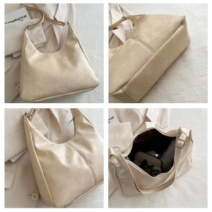 Detail view of beige hobo bag showing large capacity, soft leather texture and zipper closure