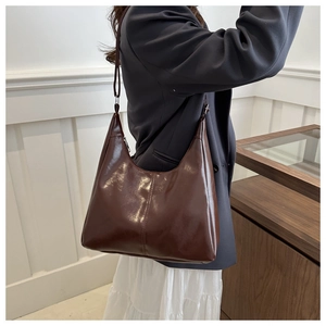 Detail of glossy brown leather crescent shoulder bag with metallic zipper and smooth finish