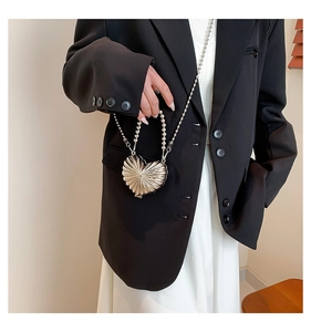 Dettaglio mini borsa argento a forma di cuore con texture metallica e catena a sfere