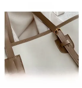 Detail showing adjustable metal buckle and embossed logo on minimalist tote bag