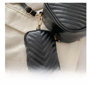 Detail of a black quilted leather mini pouch with golden zipper and clip hook attachment