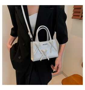 Détail d'un mini sac carré blanc avec logo argenté et bandoulière réglable chic