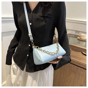 Close-up of light blue leather cylindrical bag with chunky gold chain strap detail