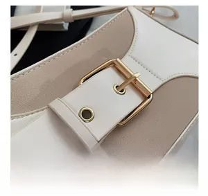 Close-up of beige leather shoulder bag showing large buckle and golden hardware