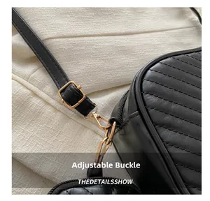Detailed close-up of golden adjustable metal buckle and quilted black leather strap texture