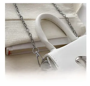 Close-up of elegant silver chain hook and metal buckle on white leather handbag