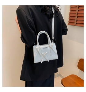 Détail du petit sac blanc brillant avec décor croisé et logo métallique chic