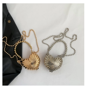 Dettaglio di mini borse in metallo a forma di cuore oro e argento con texture radiale
