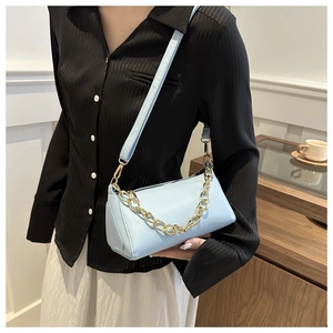 Detailed view of light blue leather baguette bag with a decorative gold chain strap