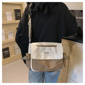 Rear view of model wearing a cream and khaki canvas messenger bag in a library setting