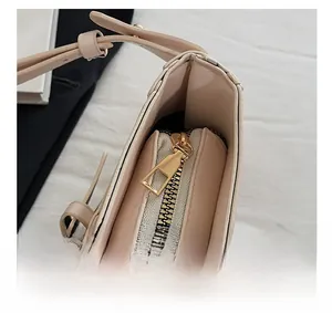 Close-up of a smooth gold metal zipper detail on a light pink faux leather shoulder bag