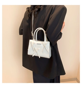 Mannequin en costume noir tenant le petit sac à main blanc à nœuds lors d'un shooting