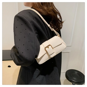 Chic cream small square shoulder bag with large gold buckle detail on black blazer