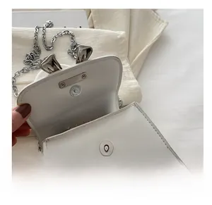 Detail view of the silver magnetic closure and textured faux leather on the white chain bag