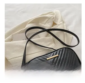 Close-up of black crossbody bag with V-shaped quilting and golden metal bar detail