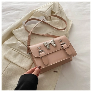 Detail of dusty pink leather crossbody bag with silver bow accent and buckles