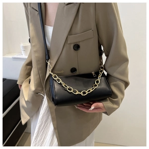 Chic black underarm bag with gold chain detail worn with a stylish beige blazer outfit