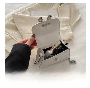 Detail view of mini white crossbody bag with silver bunny ears and chain strap showing capacity