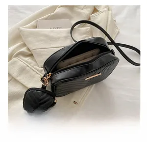Detail view of black V-quilted crossbody bag showing spacious interior and golden hardware