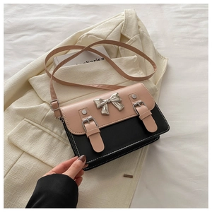 Detail of a pink and black contrast crossbody bag with silver metal bow and buckle straps