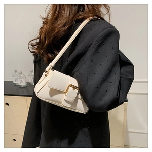 Detail of a minimalist off-white shoulder bag featuring a golden buckle and leather strap