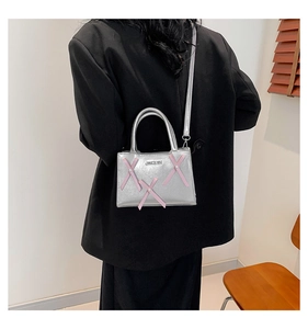 Vue détaillée du mini sac argenté métallisé avec ruban rose et bandoulière fine